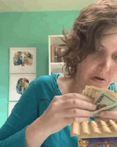 Henny sticking dollars into a Pushka, a Jewish charity box.